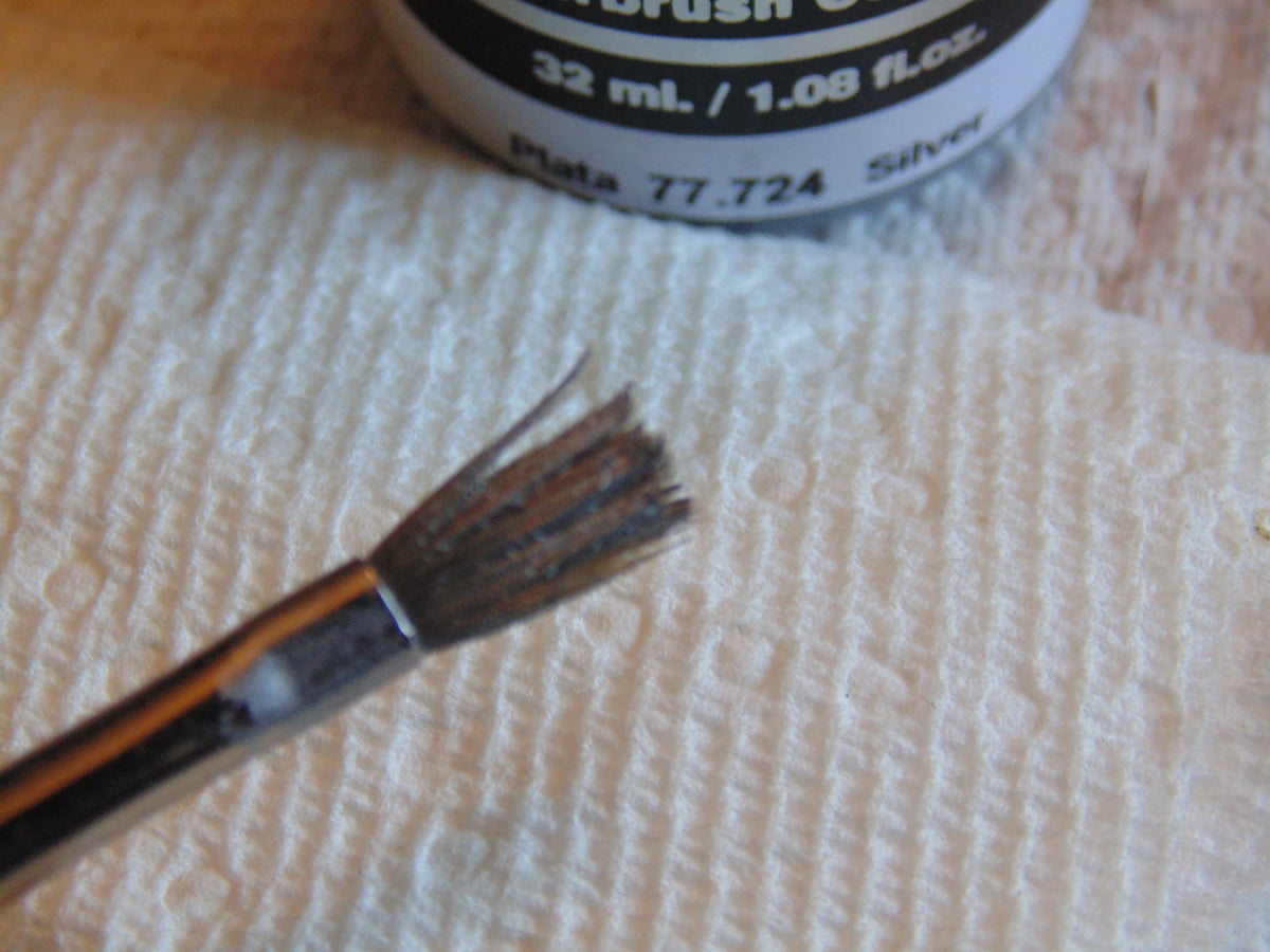 Brush Tip With Silver Paint And Brush Tip With Excess Paint On Paper Towel