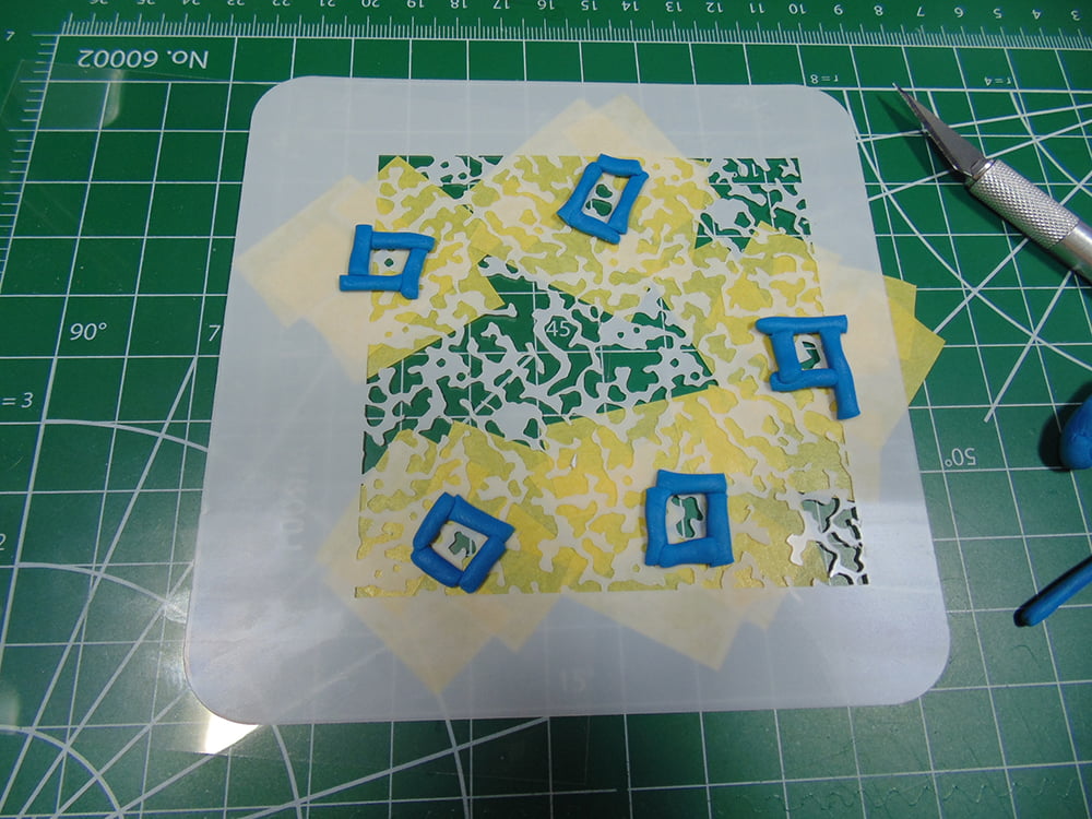 Stencil with blue squares behind yellow tape