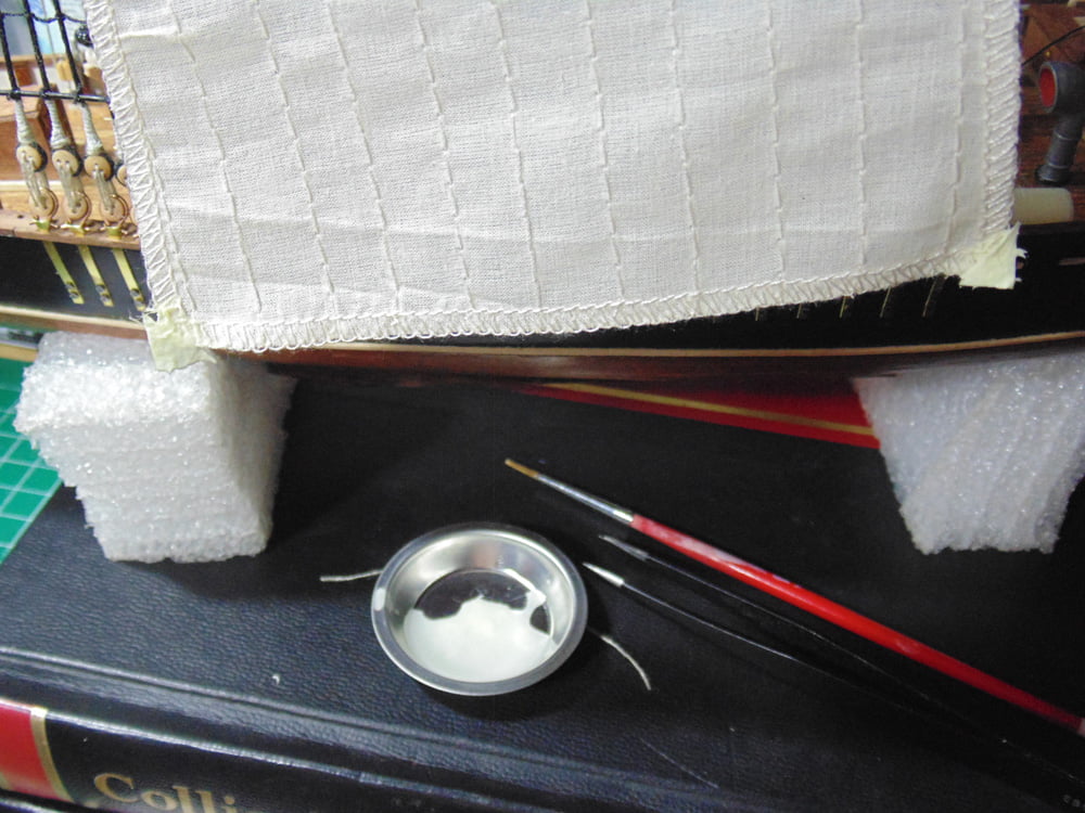 Glue in a metal cup with red brush and sail